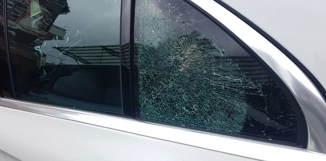 Die kaputte Fensterscheibe eines Autos. Sie ist zersplittert.